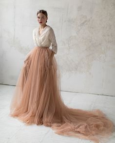 a woman is standing in a long tulle skirt