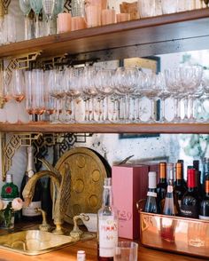 many wine glasses are lined up on the shelves in a bar with other bottles and glasses