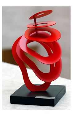 a red sculpture sitting on top of a black stand