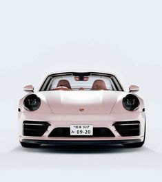 the front view of a pink sports car with two people in it's cab