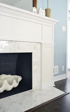 an image of a fireplace in the middle of a room with blue walls and white trim