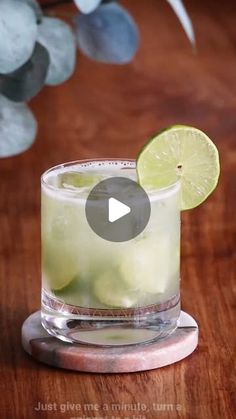 a glass filled with lemonade and lime on top of a wooden table