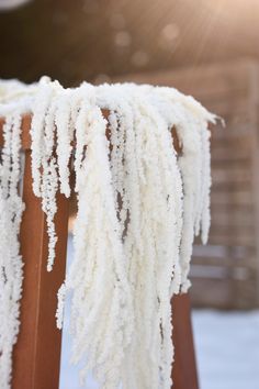 some white yarn is hanging from a wooden chair