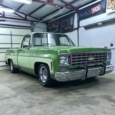 an old green truck parked in a garage