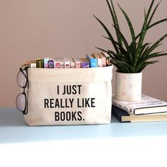 a book bag that says i just really like books next to a potted plant