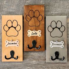 three wooden magnets with dog paw prints on them and name tags attached to them