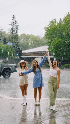 three women standing in the rain with their arms up