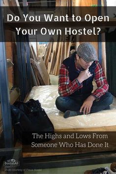 a man sitting on top of a mattress in a room filled with wooden boards and other items