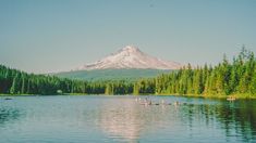 some people are out in the water with their canoes and mountains in the background