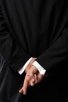 a man in a suit is holding his hands together