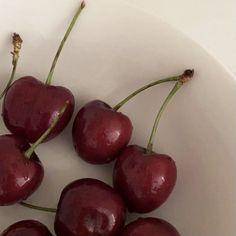 a white bowl filled with cherries on top of a table