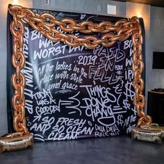 a large blackboard with gold chains hanging from it's sides in a room