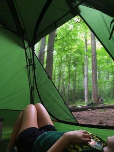 a person laying in a tent with their feet up on the ground next to a green tarp