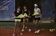 three women holding tennis balls and rackets in their hands