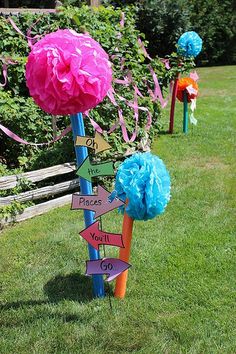 colorful paper pom poms are on poles in the grass