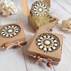 two boxes with decorative designs on them sitting next to some white flowers and twine