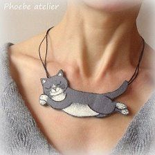 a woman wearing a gray and white cat necklace