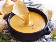 a tortilla chip being dipped into a bowl of dip