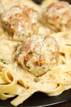 some meatballs and pasta on a black plate