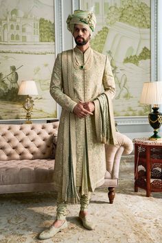 a man standing in front of a couch wearing a turban and dress clothes