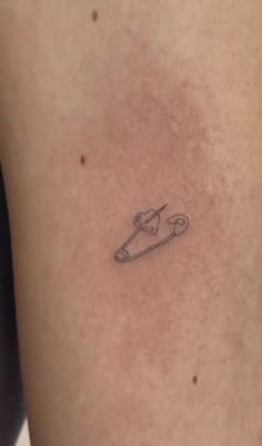 a small tattoo on the back of a woman's left arm with scissors in it