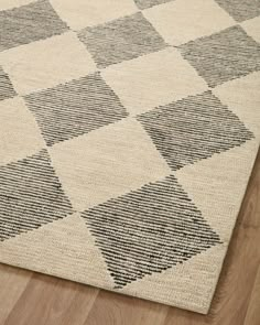 a checkered area rug with black and white squares on the bottom, along with a wooden floor