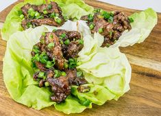 lettuce wraps with meat and green onions on a wooden cutting board, ready to be eaten