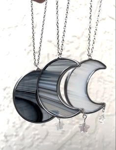 the moon and crescent shaped glass pendants are hanging from chains on a white surface