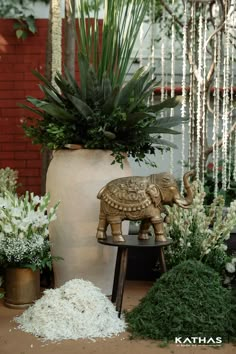 an elephant statue sitting on top of a table next to plants