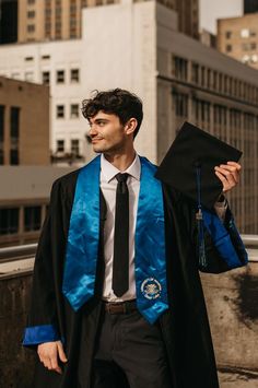 a man in a graduation gown holding his cap and gown