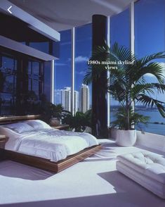 a bed sitting in the middle of a bedroom next to tall windows with ocean view