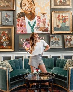 a woman standing on top of a green couch in front of a wall covered with pictures