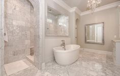 a large white bath tub sitting inside of a bathroom next to a walk in shower