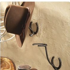 the hat is hanging on the wall next to two hooks with horseshoes in it