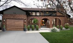 a brick house with green grass and trees in the front yard