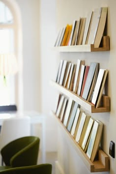 the books are lined up on the wall by the chairs in the living room area