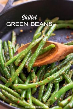 green beans are being cooked in a skillet with a wooden spoon and seasoning