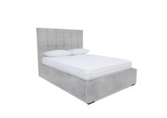 an upholstered bed with white sheets and pillows