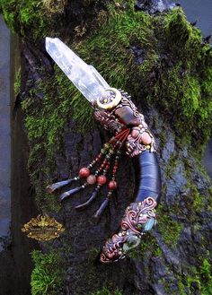 a fake lobster is sitting on the moss covered tree trunk with a knife in it's claws