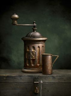 an old coffee pot with a cup next to it on top of a wooden box