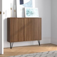 a wooden cabinet sitting on top of a hard wood floor next to a white door