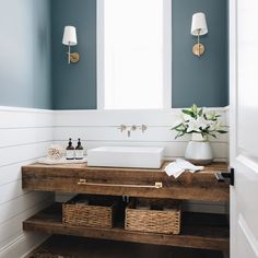 a bathroom with blue walls and white trim, including a wooden sink counter topped with two wicker baskets