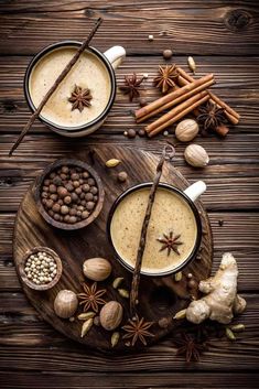 two cups of coffee with spices and cinnamon on wooden table