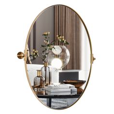 a round mirror sitting on top of a table next to a vase filled with flowers