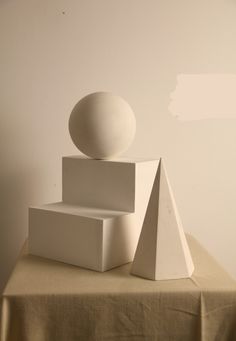 a white sculpture sitting on top of a table next to a ball and some boxes