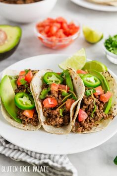 three tacos on a plate with avocado and tomatoes