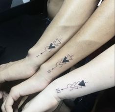 two people with matching tattoos on their arms and feet, both holding each other's hands