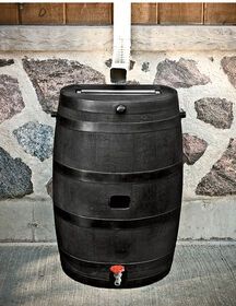 a large black barrel sitting next to a stone wall