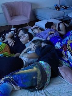 group of people laying on top of a bed in a living room next to each other