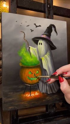 a woman is painting a halloween scene with pumpkins